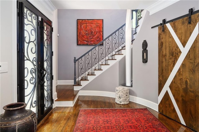 foyer with baseboards, stairs, a barn door, french doors, and wood finished floors