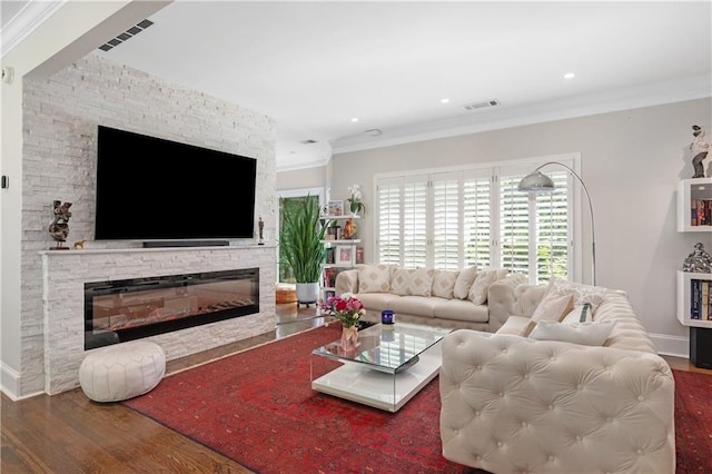 living area with visible vents, wood finished floors, and ornamental molding