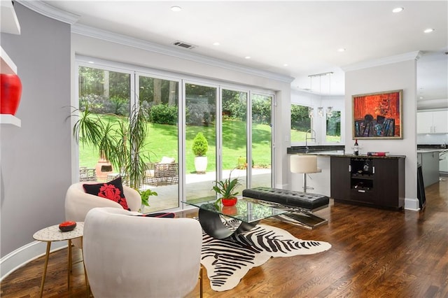 living area featuring dark wood-type flooring, recessed lighting, visible vents, and ornamental molding