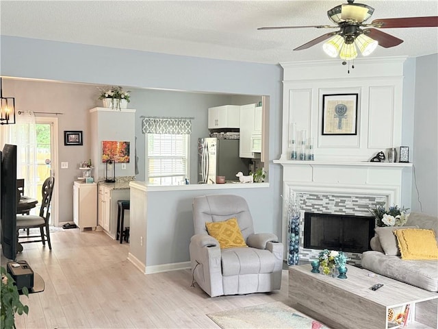 4172 Howell Park Rd, Duluth, GA 30096 - living room featuring light wood-type flooring, plenty of natural light, a ceiling fan, a textured ceiling, and a tile fireplace
