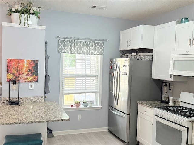 4172 Howell Park Rd, Duluth, GA 30096 - kitchen with white appliances, light wood-style floors, light stone countertops, white cabinets, and a textured ceiling