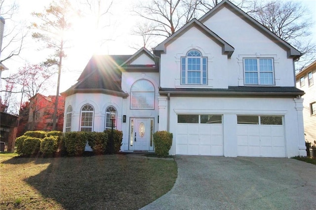 view of front facade featuring stucco siding, a front lawn, concrete driveway, and an attached garage