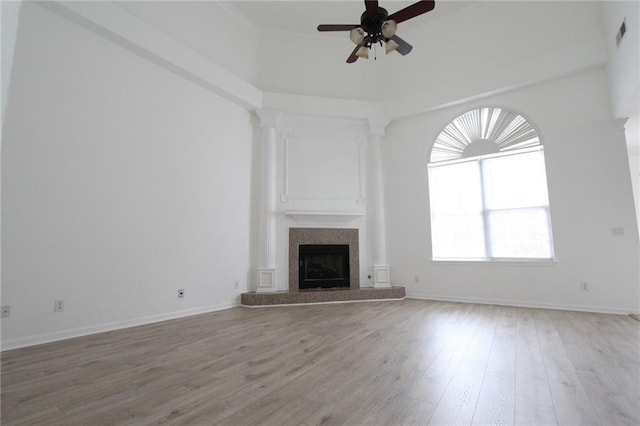 unfurnished living room with a fireplace, visible vents, ceiling fan, wood finished floors, and baseboards