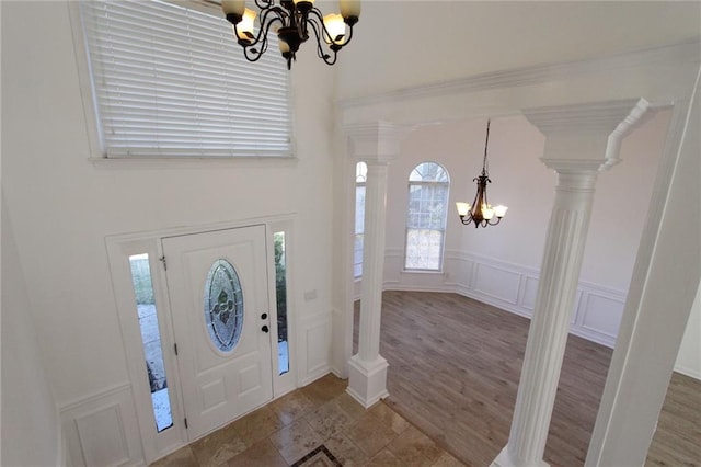 entrance foyer with decorative columns, a notable chandelier, wood finished floors, and a decorative wall