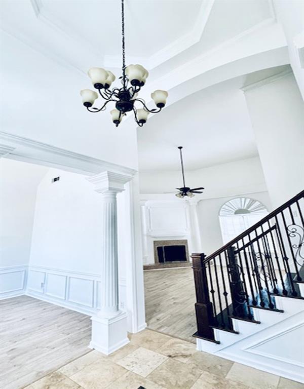 stairway featuring ceiling fan with notable chandelier and decorative columns