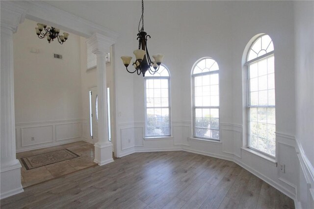 empty room featuring dark wood-type flooring, a healthy amount of sunlight, and a notable chandelier