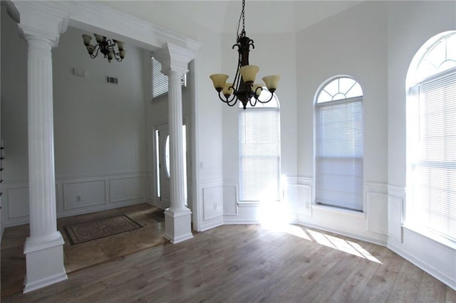 unfurnished dining area with a chandelier and decorative columns