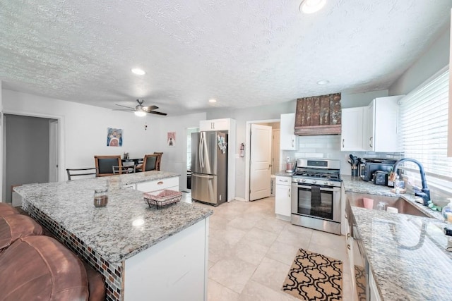 1279 Skyhaven Rd SE, Atlanta, GA 30316 - kitchen featuring appliances with stainless steel finishes, a kitchen island, ceiling fan, white cabinets, and tasteful backsplash