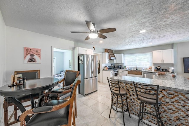 1279 Skyhaven Rd SE, Atlanta, GA 30316 - kitchen featuring stainless steel appliances, white cabinetry, ceiling fan, a breakfast bar, and light stone countertops