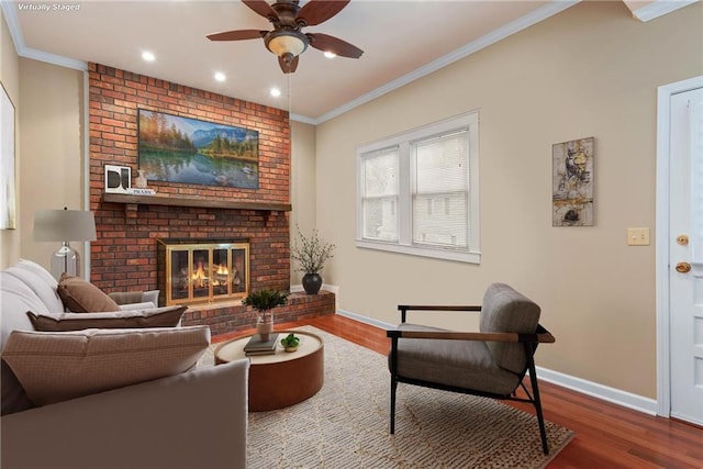 living room with a brick fireplace, hardwood / wood-style flooring, ornamental molding, and ceiling fan