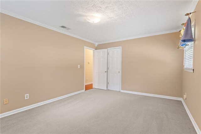 unfurnished room with carpet floors, ornamental molding, and a textured ceiling