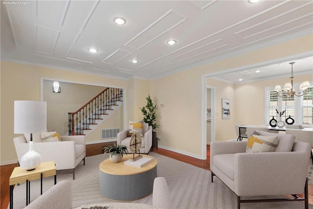 living room with crown molding, a chandelier, and light hardwood / wood-style flooring