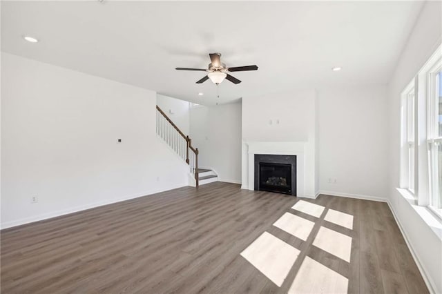 unfurnished living room featuring ceiling fan and dark wood-type flooring