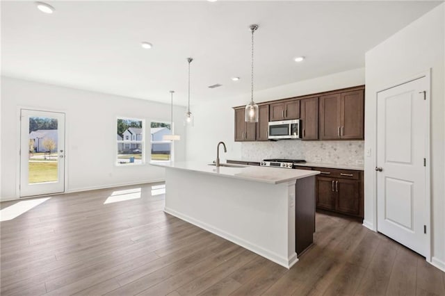 kitchen featuring decorative light fixtures, a center island with sink, dark brown cabinets, and sink