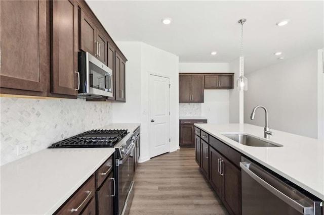 kitchen featuring dark brown cabinetry, sink, stainless steel appliances, and decorative light fixtures