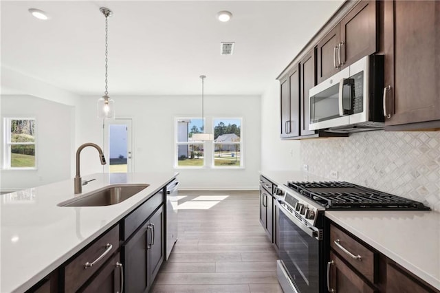 kitchen featuring dark brown cabinets, sink, stainless steel appliances, and decorative light fixtures