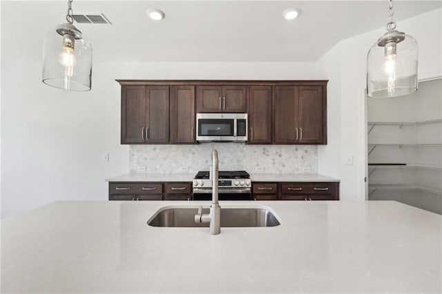 kitchen featuring pendant lighting, dark brown cabinetry, stainless steel appliances, and tasteful backsplash