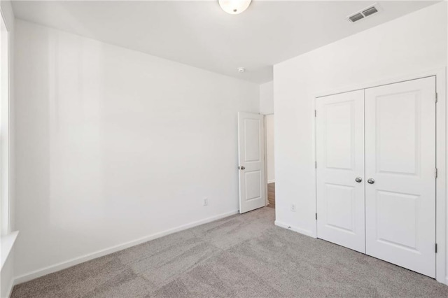 unfurnished bedroom with light carpet and a closet