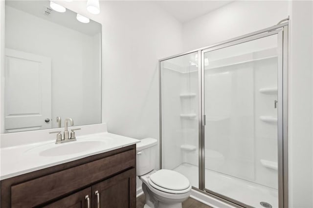 bathroom with vanity, toilet, and a shower with door