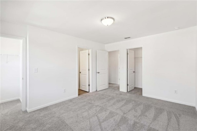 unfurnished bedroom featuring light colored carpet, a spacious closet, and a closet