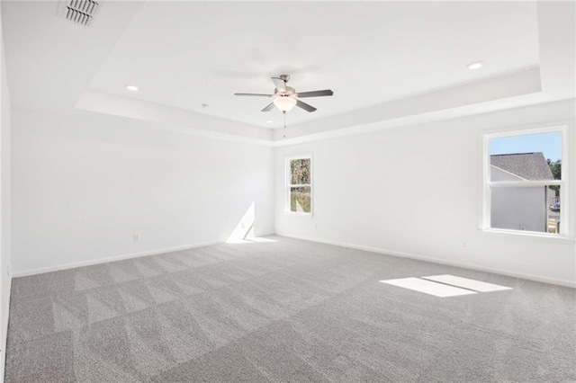 carpeted empty room featuring a raised ceiling and ceiling fan