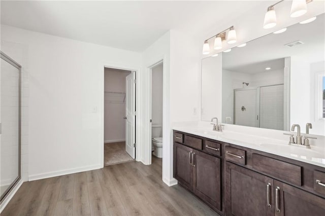 bathroom with hardwood / wood-style flooring, vanity, toilet, and a shower with door