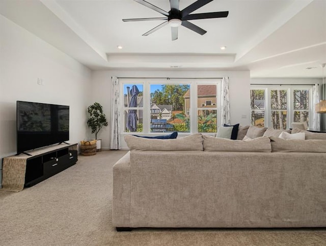 carpeted living room featuring ceiling fan and a raised ceiling