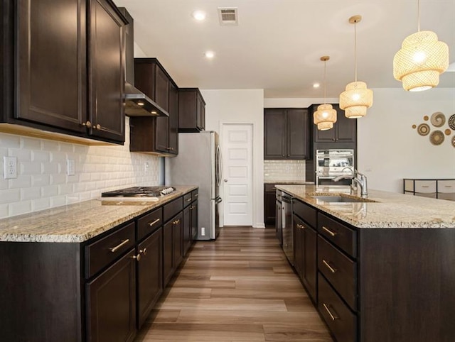 kitchen featuring stainless steel appliances, decorative light fixtures, sink, and dark brown cabinets