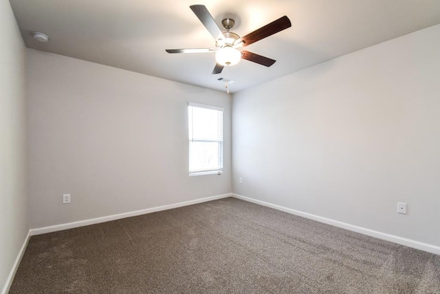 empty room with dark colored carpet and ceiling fan