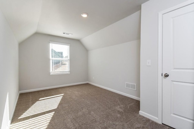 bonus room with dark carpet and lofted ceiling