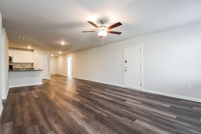 unfurnished living room with ceiling fan, dark wood-type flooring, and sink