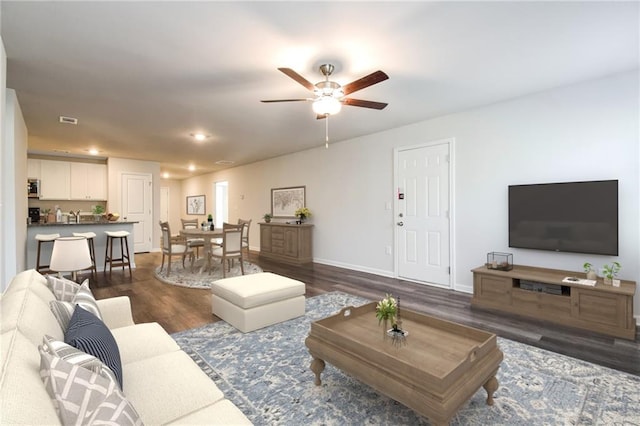 living room with ceiling fan and dark hardwood / wood-style flooring