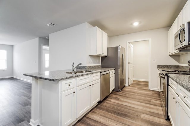 kitchen with sink, stainless steel appliances, light hardwood / wood-style flooring, stone countertops, and white cabinets