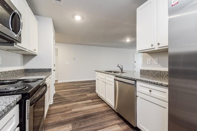 kitchen featuring appliances with stainless steel finishes, white cabinetry, and dark stone counters