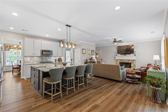 7537 Brookstone Cir, Flowery Branch, GA 30542 - kitchen featuring stainless steel appliances, wood finished floors, ornamental molding, white cabinetry, and a kitchen bar