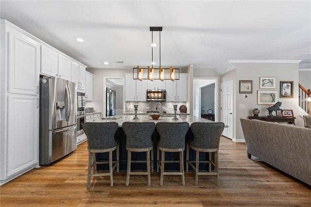 7537 Brookstone Cir, Flowery Branch, GA 30542 - kitchen featuring appliances with stainless steel finishes, white cabinets, recessed lighting, decorative backsplash, and a kitchen breakfast bar