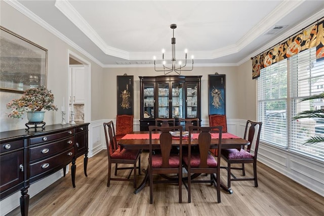 7537 Brookstone Cir, Flowery Branch, GA 30542 - dining space featuring light wood finished floors, a tray ceiling, a chandelier, wainscoting, and a decorative wall