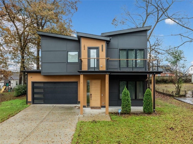 contemporary house featuring a garage, concrete driveway, a front lawn, and a balcony