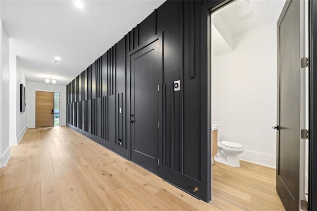 hallway featuring light wood finished floors and baseboards