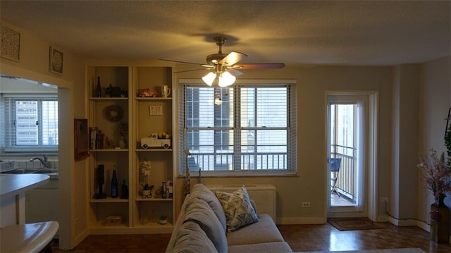 living room featuring ceiling fan, plenty of natural light, sink, and a textured ceiling