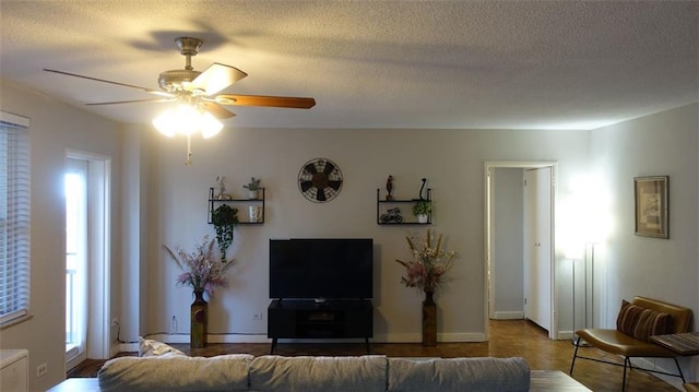 living room featuring ceiling fan, plenty of natural light, and a textured ceiling