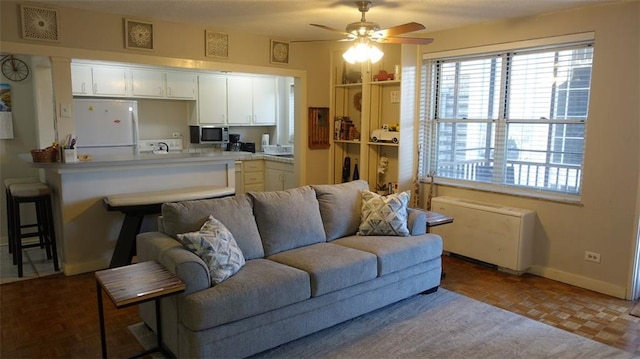 living room featuring ceiling fan, light parquet flooring, and radiator