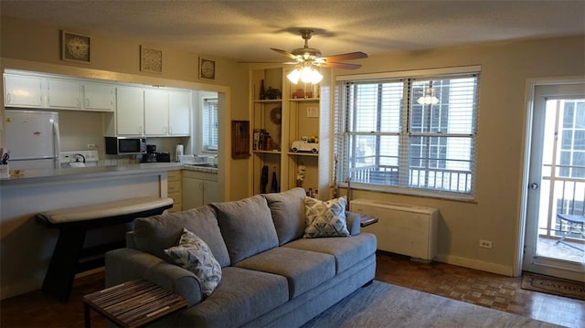 living room with ceiling fan, parquet flooring, radiator heating unit, and a textured ceiling