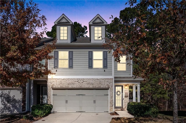 view of front of home with concrete driveway, brick siding, and an attached garage