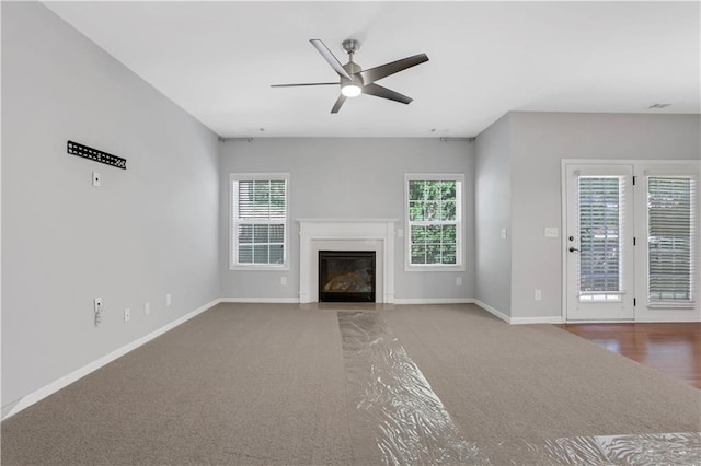 unfurnished living room featuring ceiling fan and carpet floors