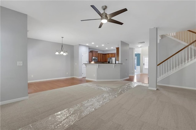 unfurnished living room featuring light hardwood / wood-style floors and ceiling fan with notable chandelier