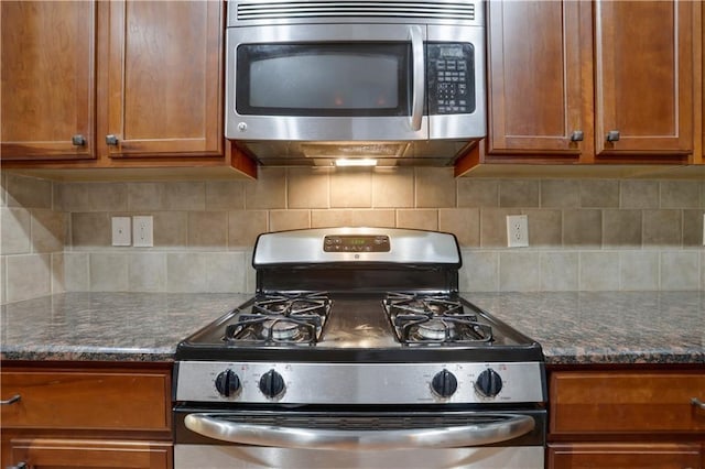 kitchen featuring dark stone counters, decorative backsplash, and stainless steel appliances