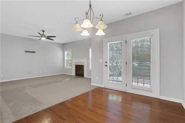 unfurnished living room with hardwood / wood-style floors, a healthy amount of sunlight, and ceiling fan with notable chandelier