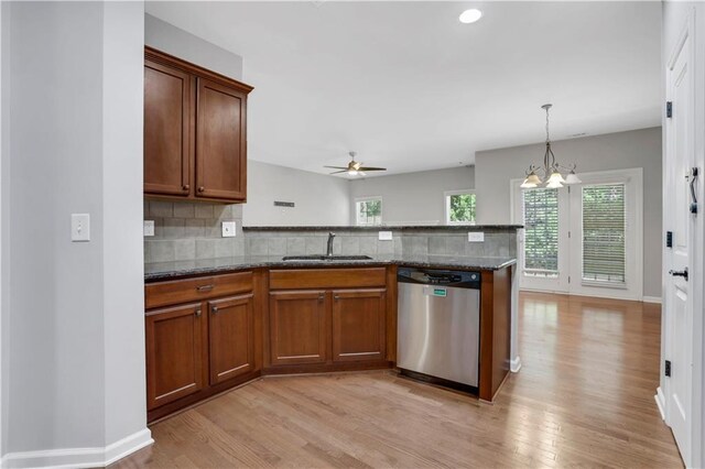 kitchen featuring sink, dishwasher, dark stone counters, and light hardwood / wood-style flooring