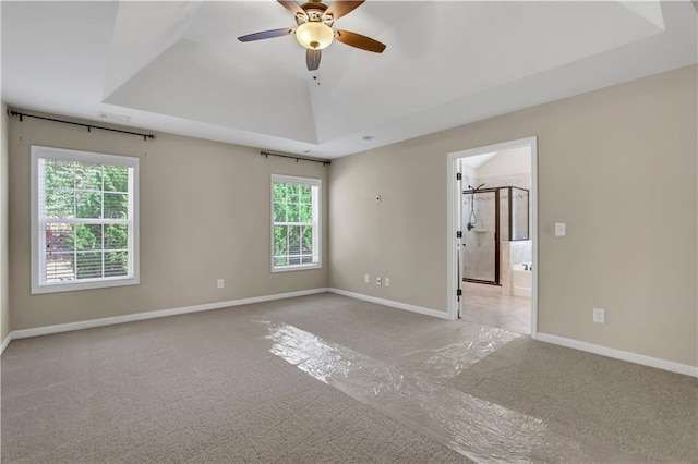 spare room with a tray ceiling, ceiling fan, plenty of natural light, and light colored carpet